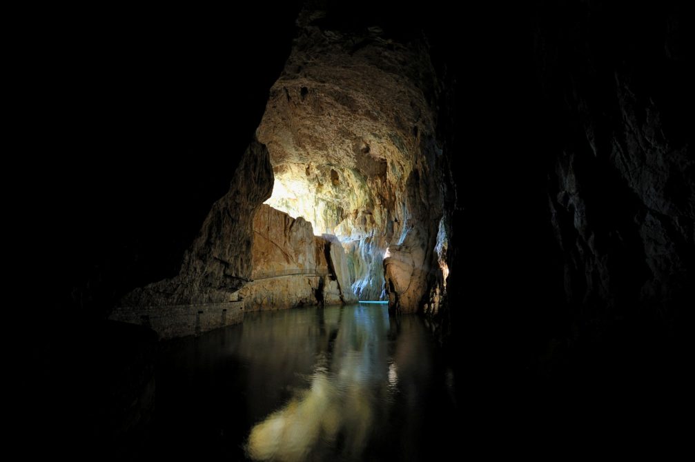 The Reka river flowing inside Skocjan Caves with the light filtering through the cave