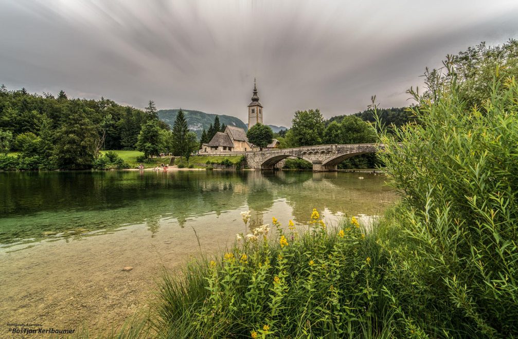 Lake Bohinj with a bridge and the Church of St John the Baptist in the background