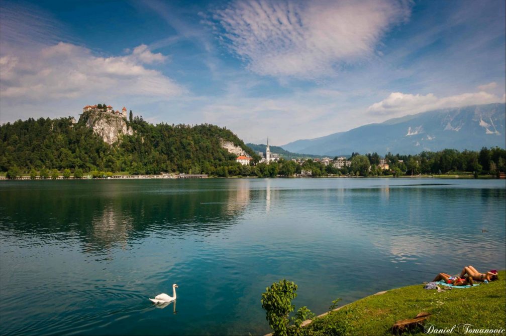 Lake Bled with its cliff-top castle and a few people sunbathing on the shore