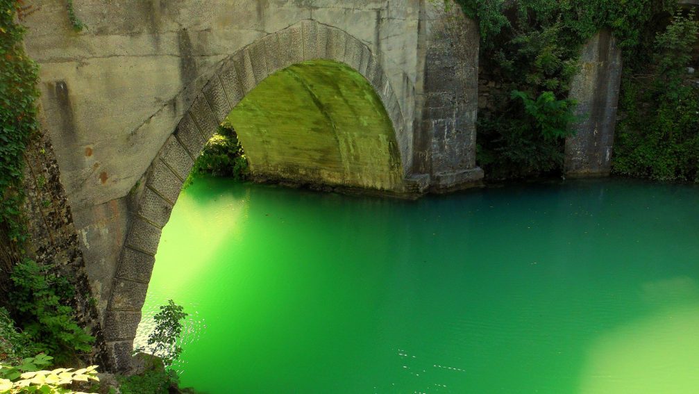 The illuminated Soca River under the bridge at Most na Soci looks like a sparkling emerald