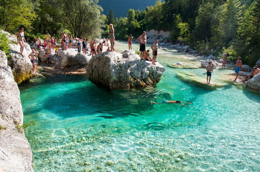 The locals and visitors swimming and sunbathing in the Soca river in Slovenia