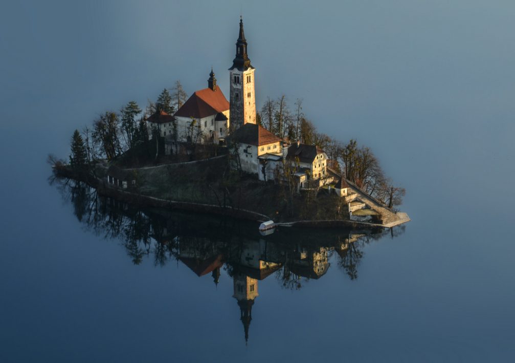 An elevated view of Bled Island with a Gothic church on it in snowless winter time