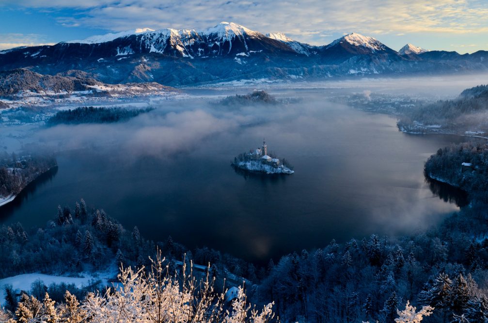 An elevated view of Lake Bled in winter with fresh snow all around