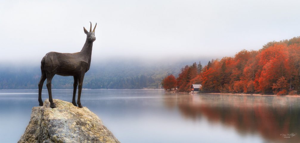 Statue of Goldhorn chamois or Zlatorog with Lake Bohinj in the background