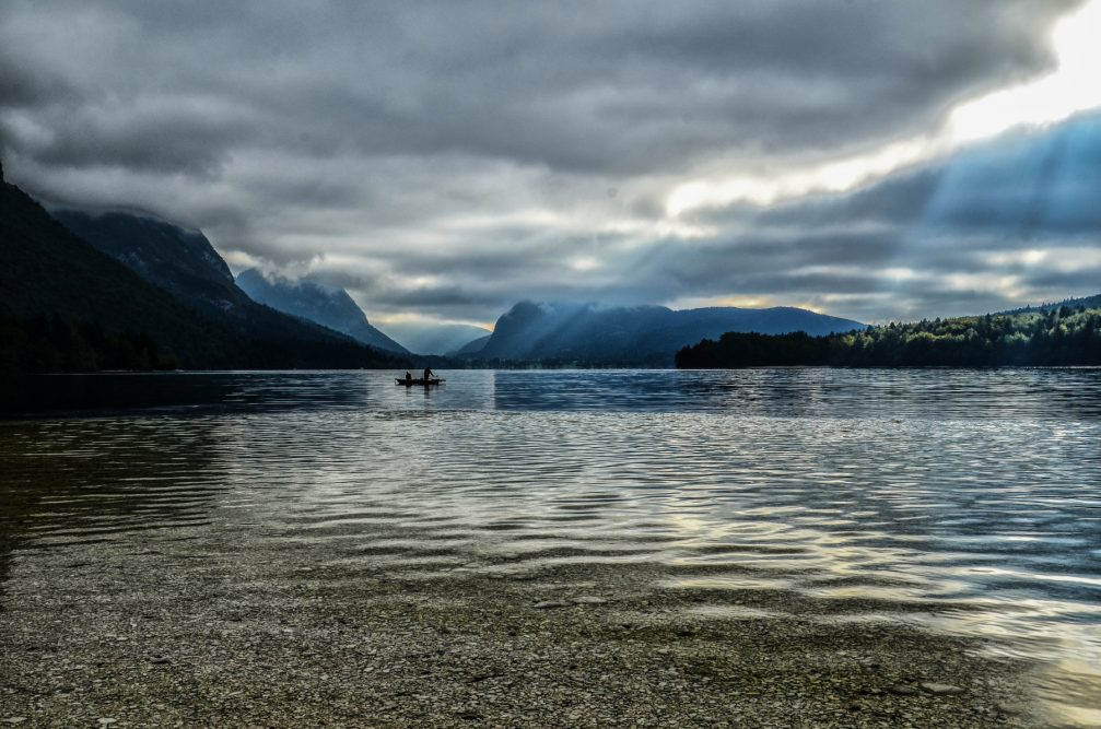 A boat in Lake Bohinj on a moody day with sunrays peaking through the clouds