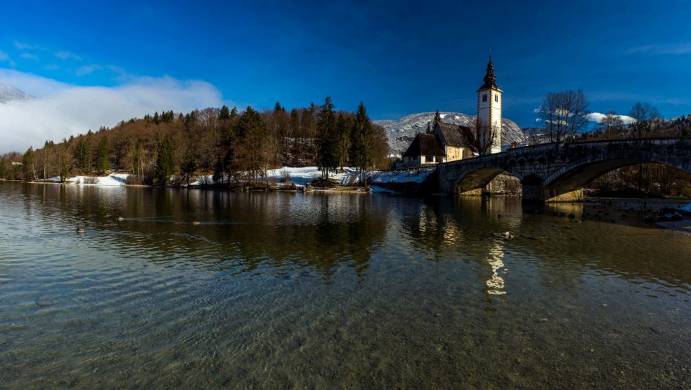 Lake Bohinj with a stone bridge and the church of St John the Baptist