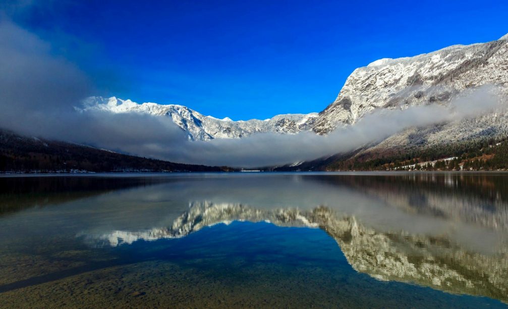 Lake Bohinj in Triglav National Park, Slovenia with snow-capped mountains on all sides