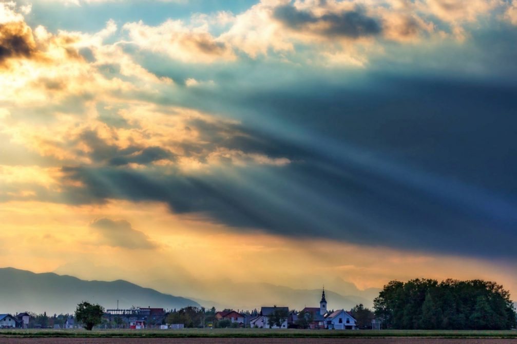 Sun rays shining through clouds in Sencur, a small town in northwestern Slovenia