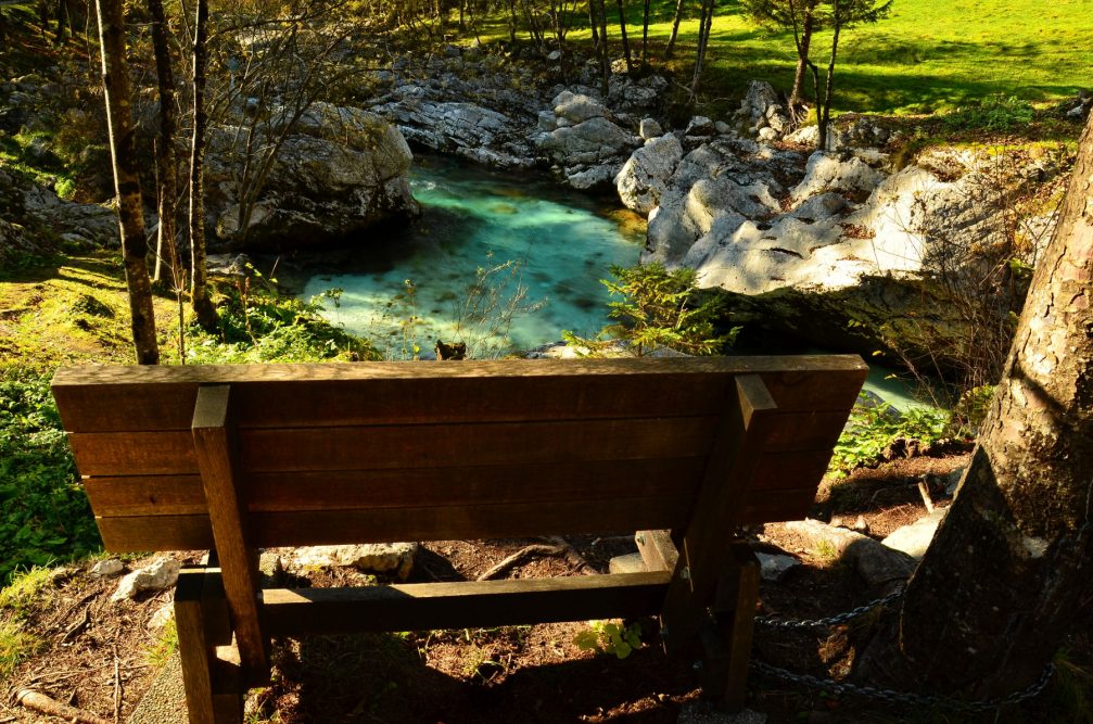 A wooden bench next to the Soca River in the Trenta Valley, Slovenia