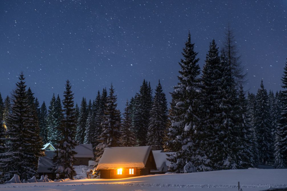 A group of Wooden huts covered with a thick layer of fresh snow at night at the Pokljuka Plateau in Slovenia