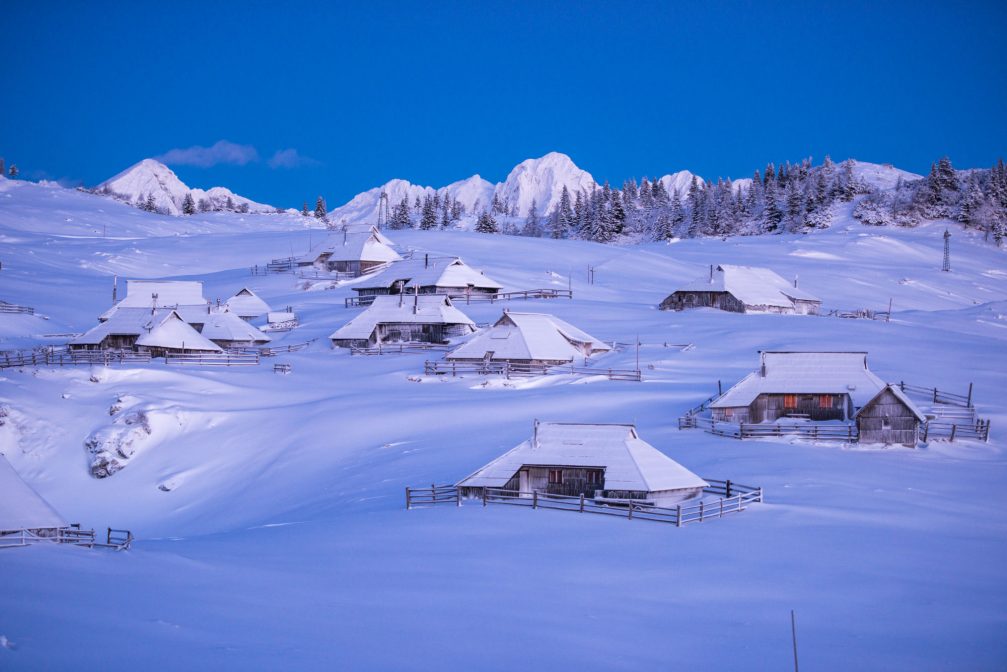 Shingle-roofed herdsmen’s huts on the Velika Planina plateau covered with snow in the winter time