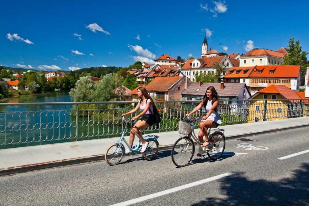 Two female cyclists on the Kandija Bridge or the Old Bridge in Novo Mesto, Slovenia