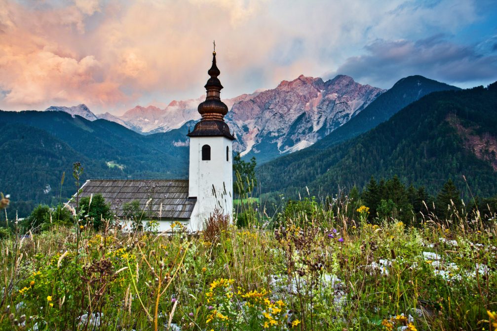 The old church of St. Oswald in Jezersko surrounded by wildflowers in spring