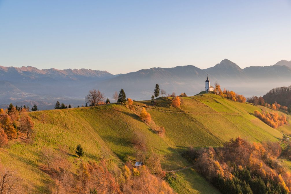 An early morning view of the church of Saints Primus and Felician in Jamnik, Slovenia in autumn at sunrise