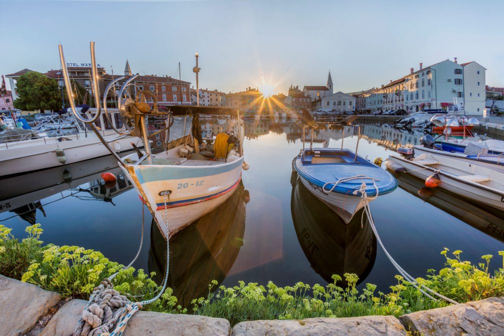 Morning sun rays at the fishing harbour of the old Mediterranean town of Izola in Slovenia