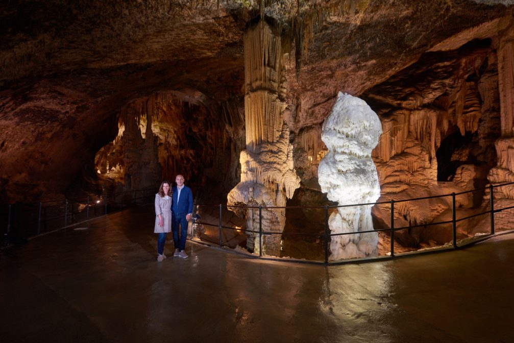 A couple posing next to the brilliant stalagmite inside the Postojna Cave in Slovenia
