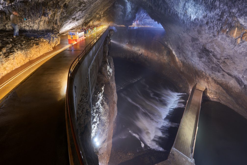 A train passing the bridge over the Pivka river inside Postojna Caves in Slovenia