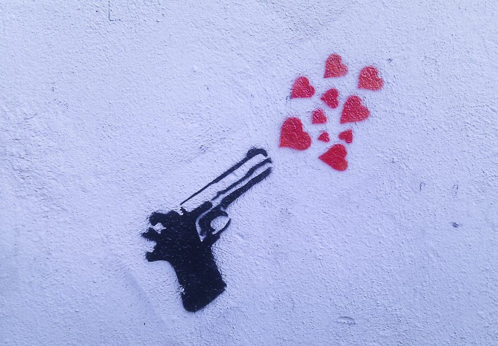 A graffiti of a gun shooting out hearts