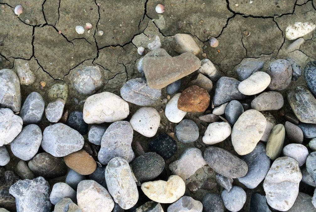 A heart shaped stone on a beach with some pebbles