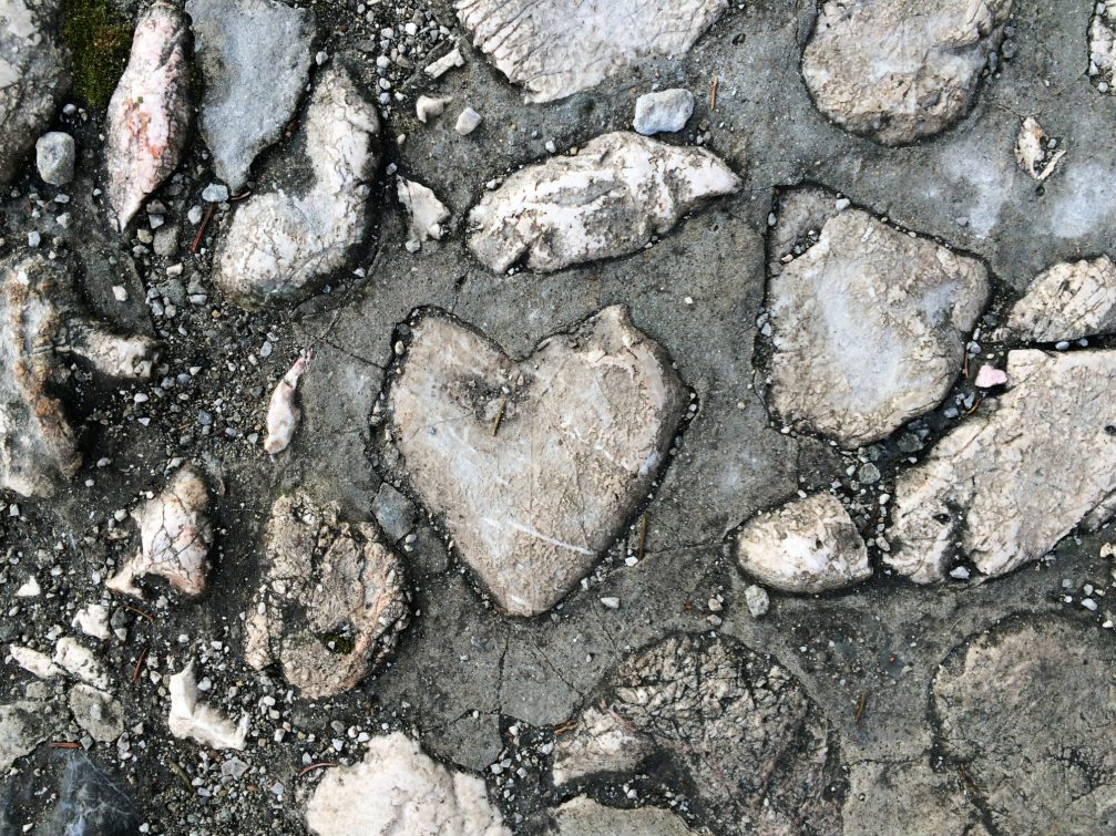 A grey heart shaped stone on the ground