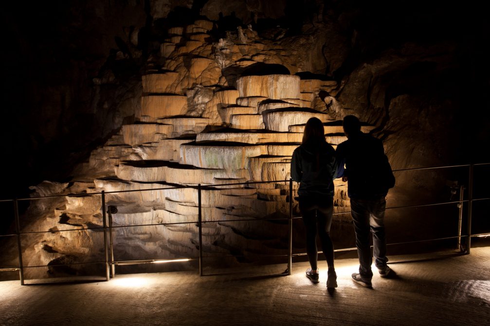 A couple of visitors looking at the terraces of precipitated calcium carbonate inside the Skocjan Caves in Slovenia