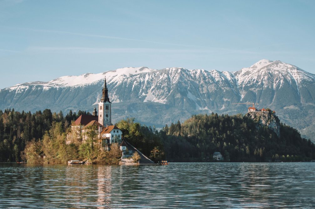 Lake Bled in Slovenia with its island, a medieval cliff-top castle and a backdrop of snow-capped mountains