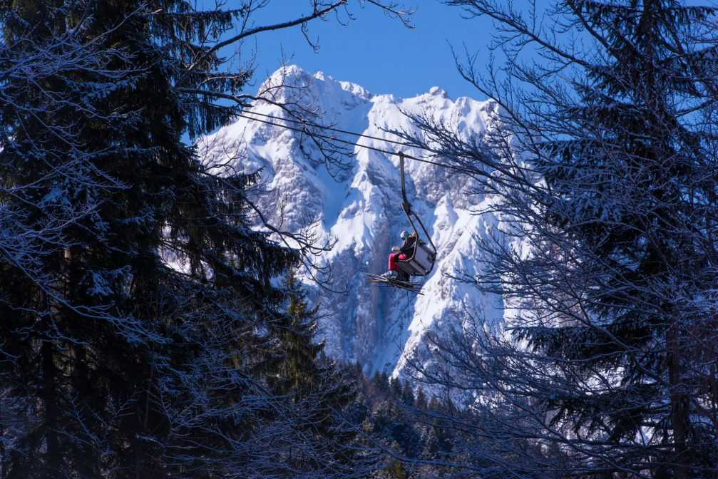 Skiers ride chair lift at Kranjska Gora Ski Resort with mountains in the background