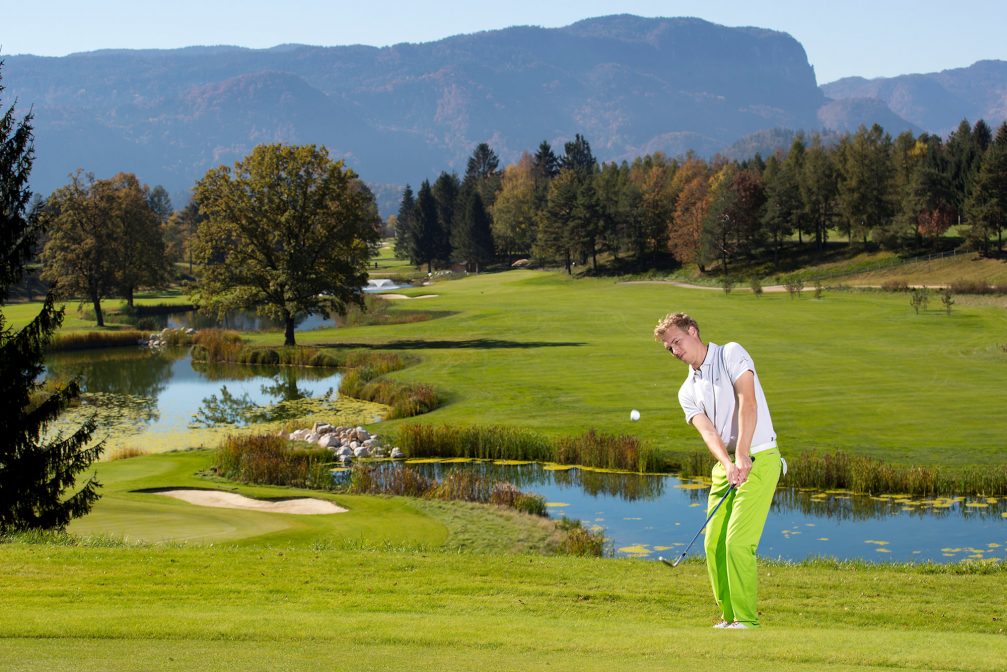 A golfer in green trousers playing golf at Kings Course at Royal Bled Golf in Slovenia