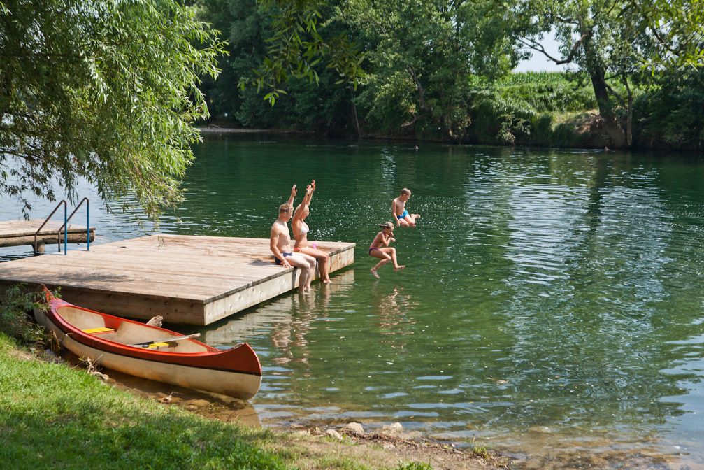 A group of people swimming in the Kolpa River at Camp Podzemelj in Slovenia