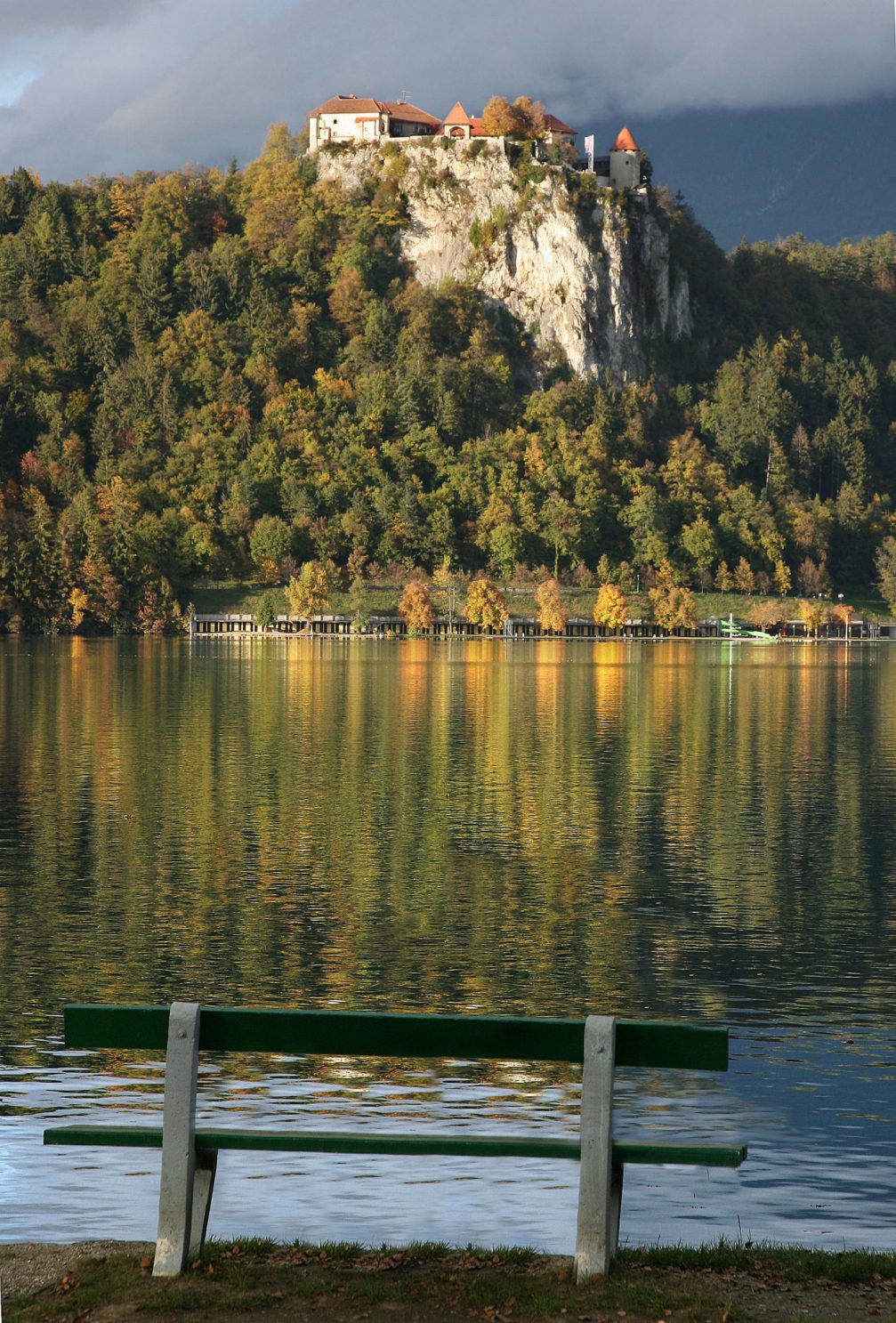 A bench with a view of Bled Castle in the autumn season
