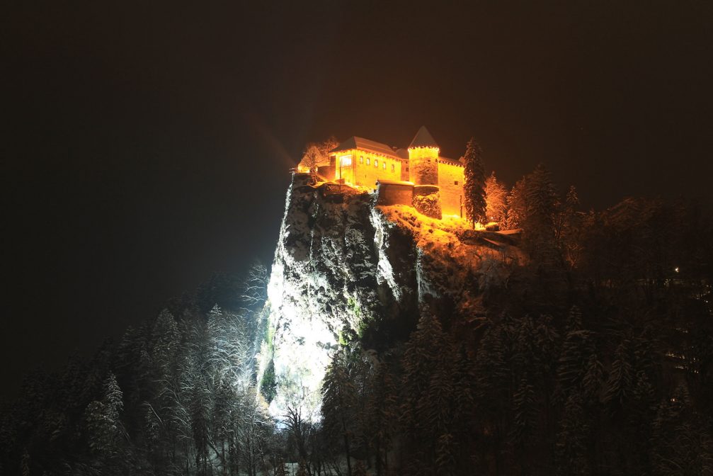 Bled Castle lit up at night in winter