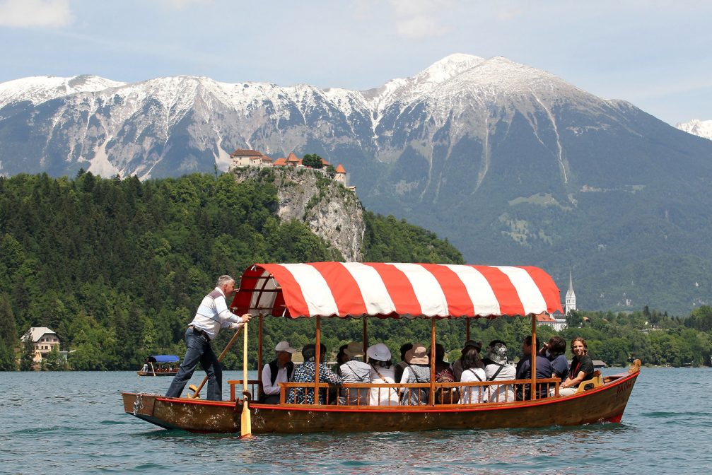 Traditional wooden Pletna boat on Lake Bled with Bled Castle in the background