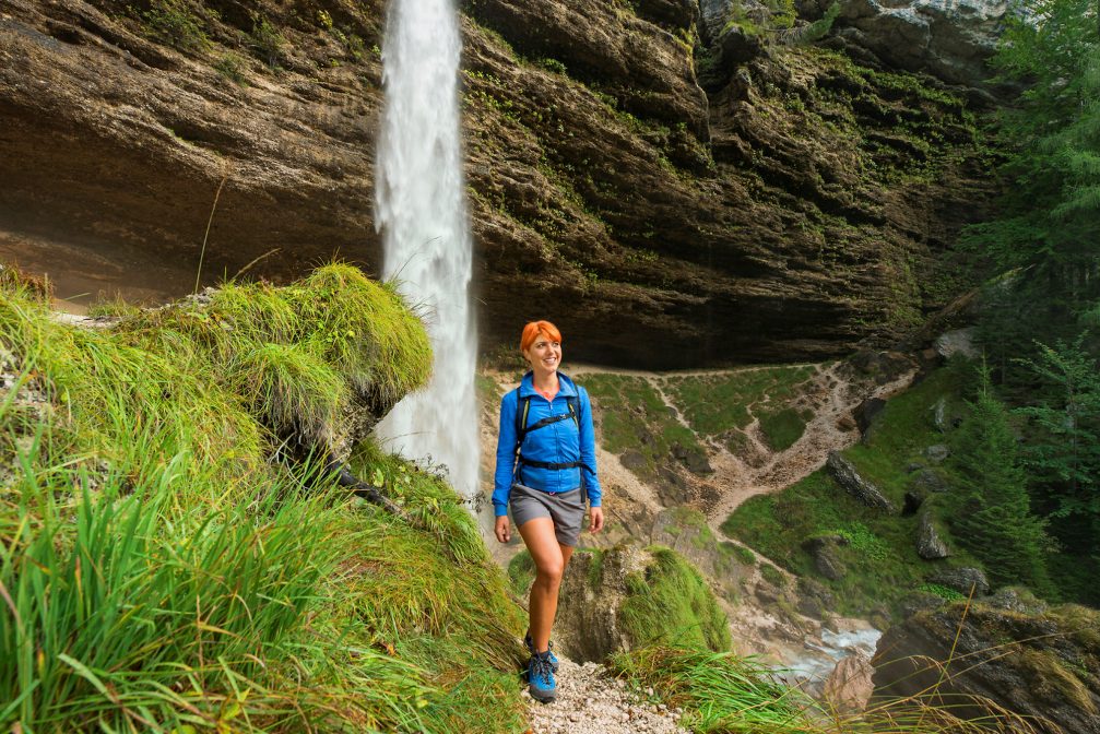 A female hiker posing in front of Pericnik Waterfall in Slovenia