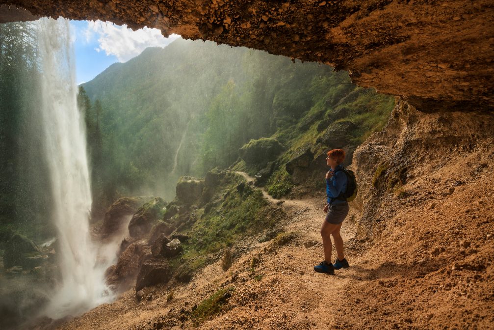 A female hiker posing on a hiking trail behind Pericnik Waterfall in Slovenia