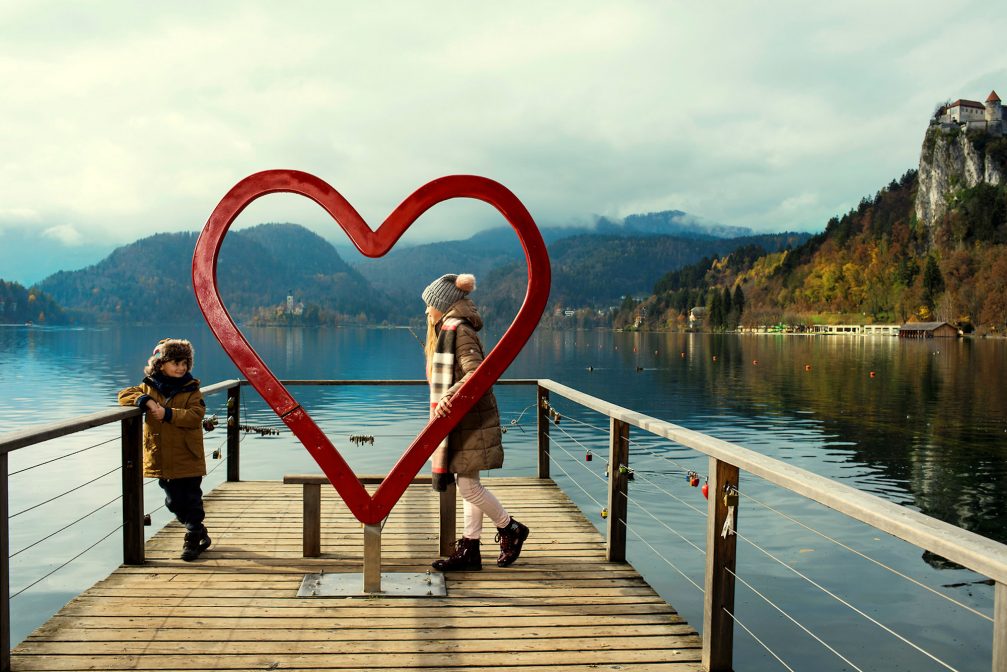 A couple of children on a wooden pier with a big red heart at Lake Bled