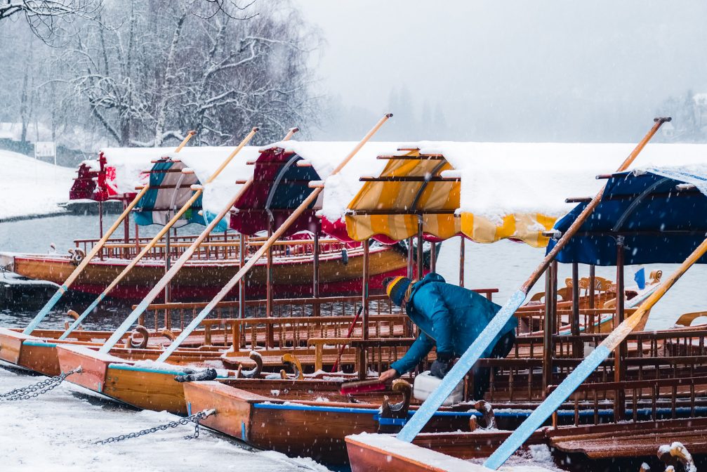 Traditional pletna boats covered in snow on Lake Bled in the winter