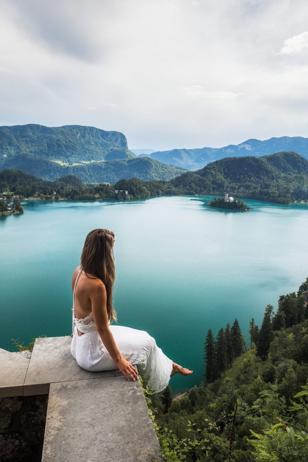 A bride in a wedding dress watching Lake Bled from Bled Castle