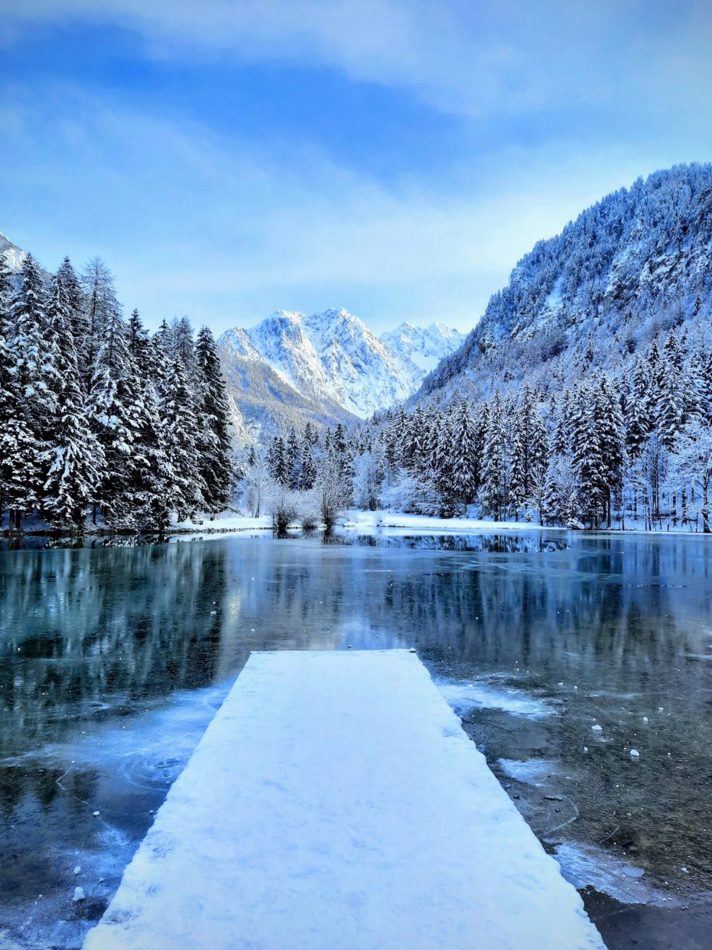 Partially frozen Lake Plansar in Jezersko in winter with Kamnik-Savinja Alps in the background