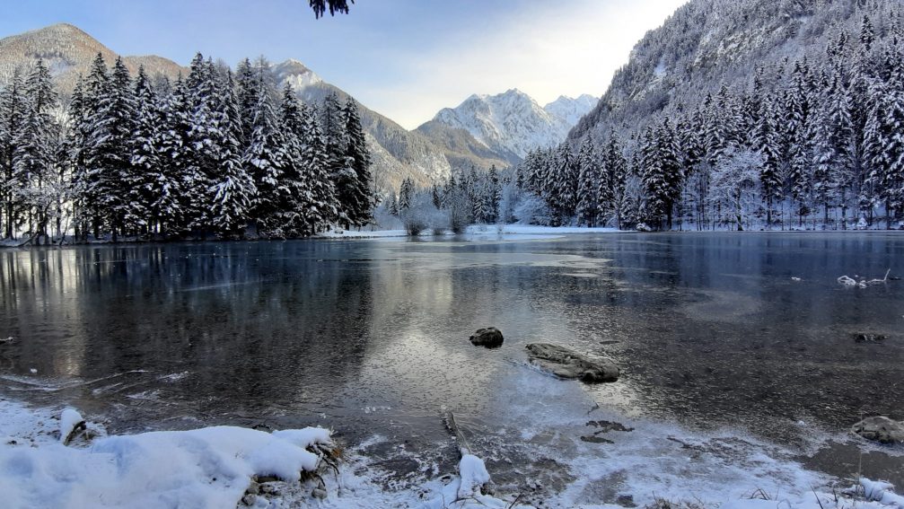 Frozen Plansar Lake in Jezersko in winter with Kamnik-Savinja Alps in the background
