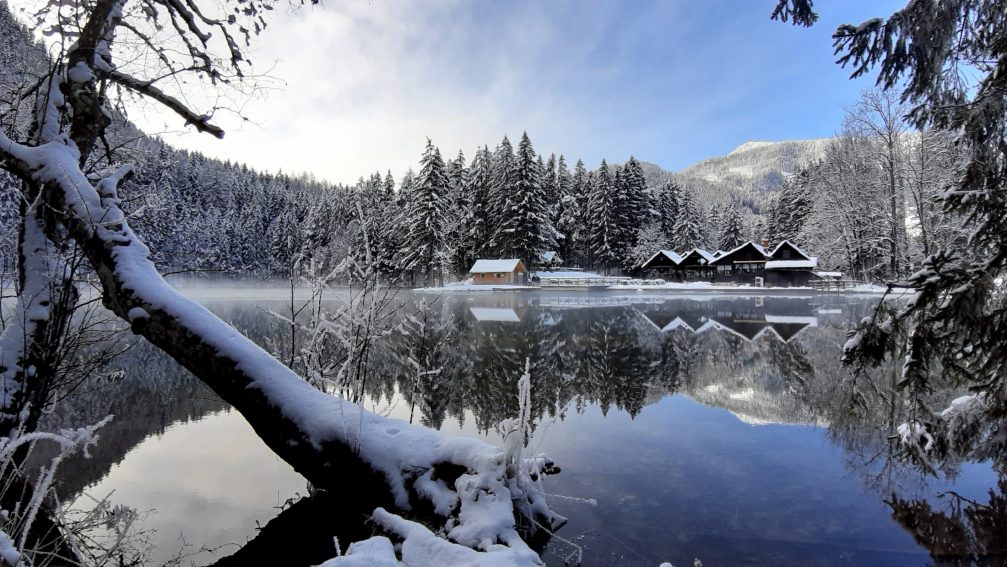 Partially frozen Plansar Lake in Jezersko in winter with mountains in the background