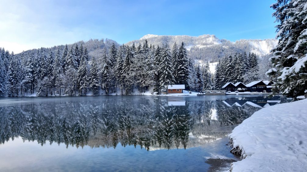 Lake Plansar in Jezersko frozen over in winter with Slovenian Alps in the background