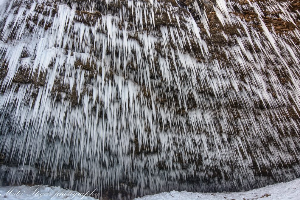 Numerous icicles on the rocky wall behind Waterfall Pericnik in winter