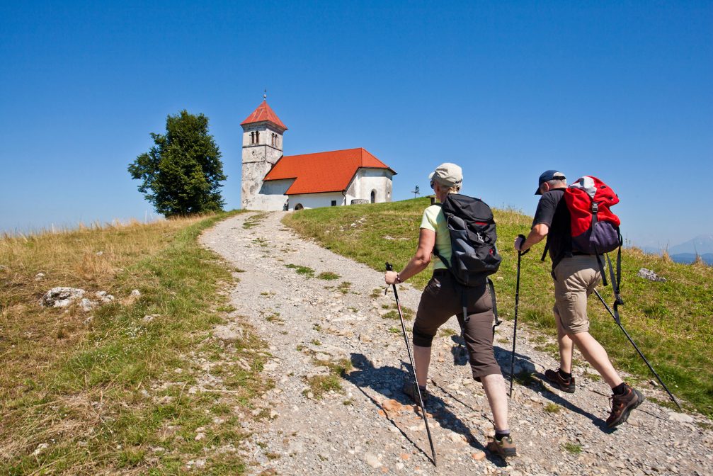 A group of hikers at the hilltop Church of St. Anne above Ljubljana Marshes