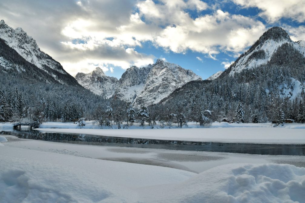 A partially frozen Lake Jasna in winter with Slovenian Alps in the background
