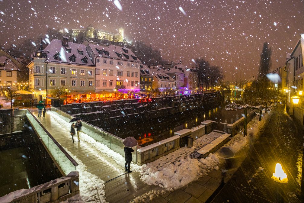 Ribja Brv footbridge in Ljubljana Old Town in winter while snowing