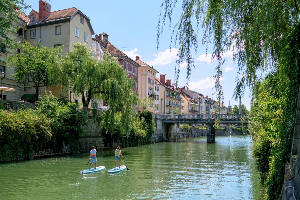 Stand up paddle boarders on Ljubljanica River at Cobblers Bridge in Ljubljana