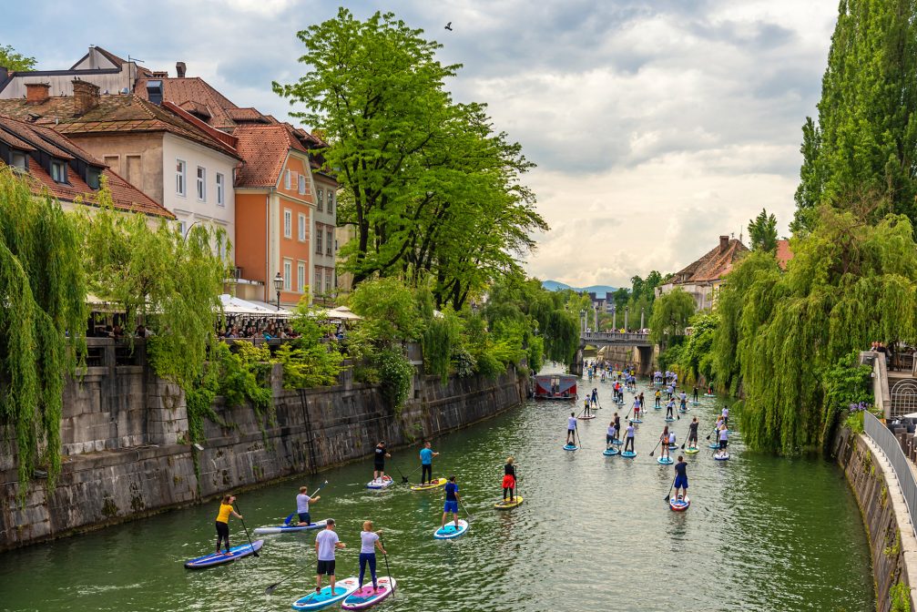 A group of tourists stand up paddle boarding on Ljubljanica River in Ljubljana