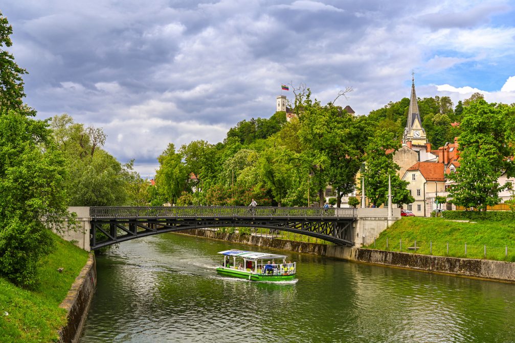 A green tourist boat on Ljubljanica River in Ljubljana