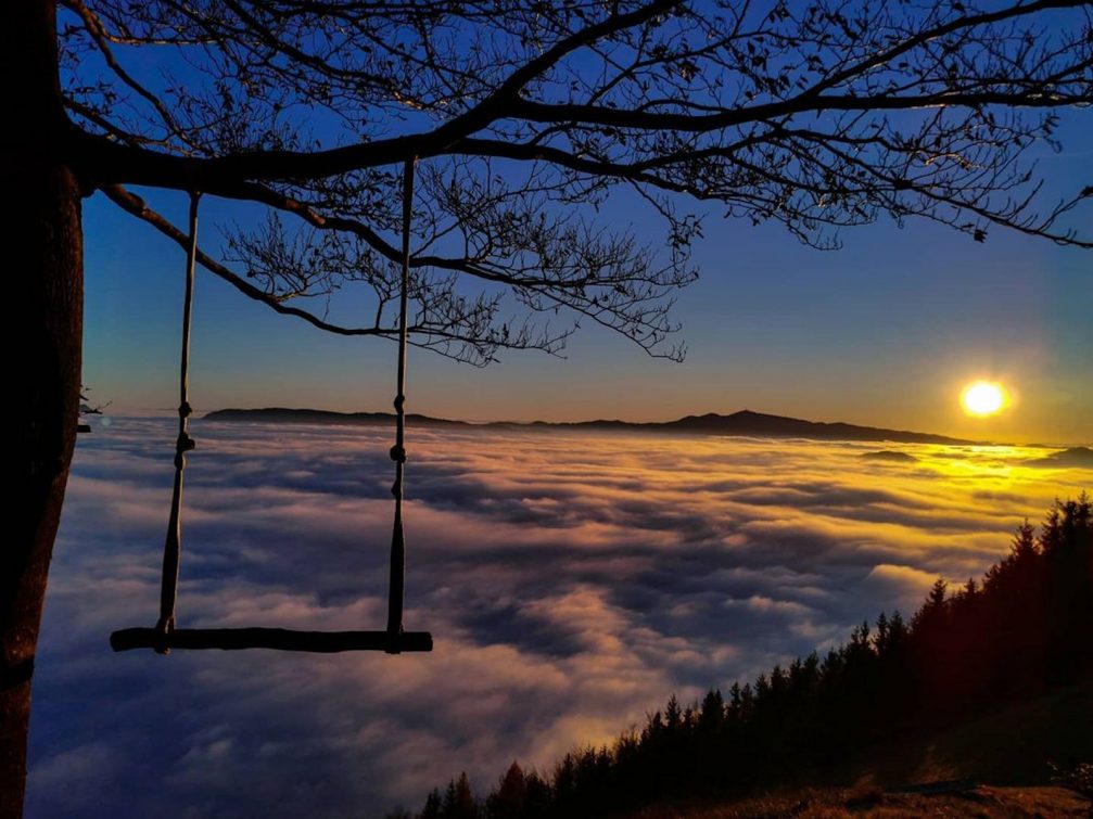 A swing on the Malic Hill above clouds at sunset