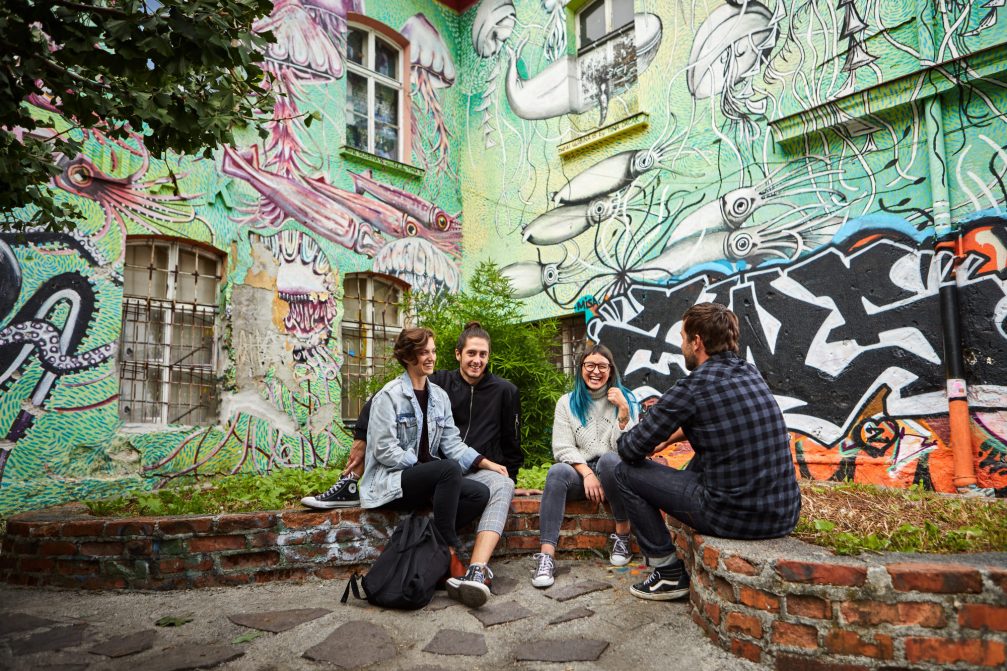 A group of artist at Metelkova City in Ljubljana with colourful graffiti in the background